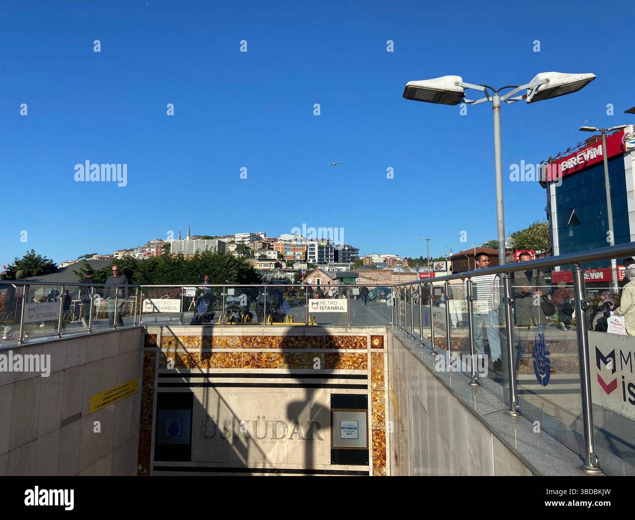Urban scene with pedestrian bridge, street signs, and cityscape under a clear blue sky in Istanbul. - Smartphone Captured Stock Image