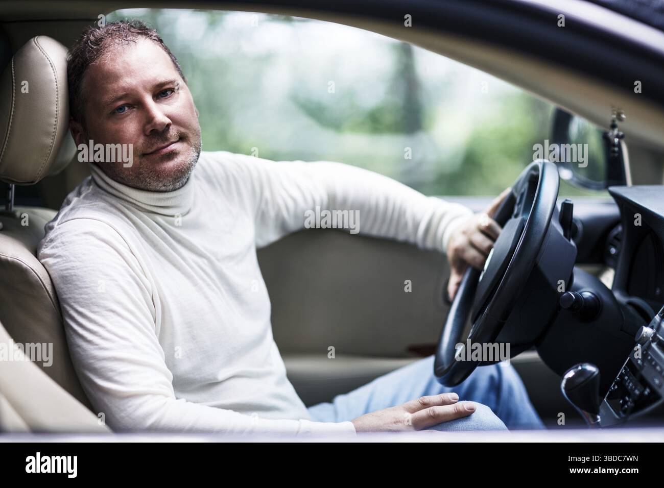 Smiling middle aged handsome man sitting in the car Stock Photo