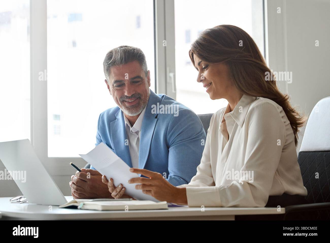 Two executives team working on laptop discussing documents at office meeting. Stock Photo