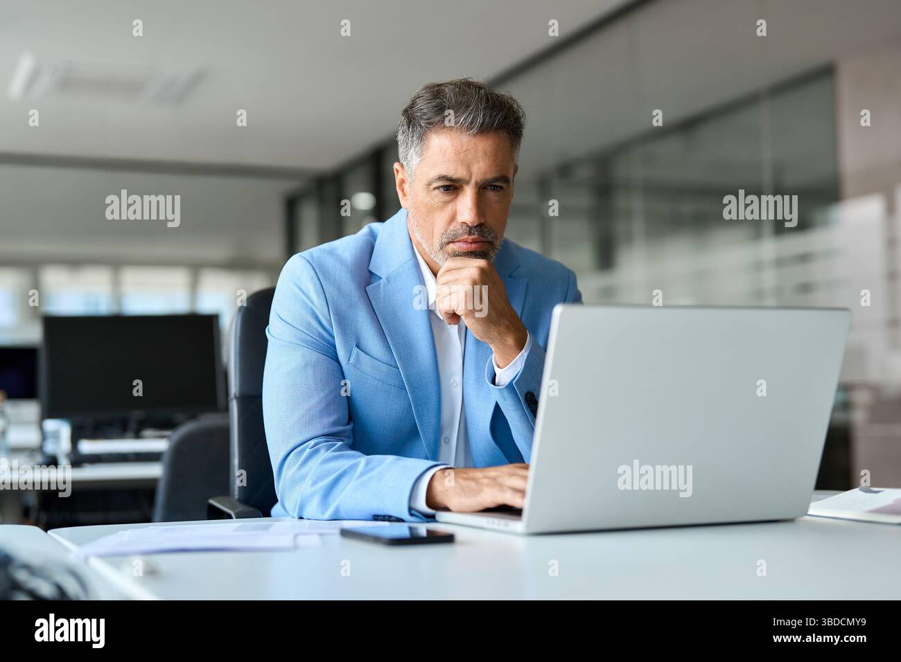 Serious busy middle aged professional business man using laptop in office. Stock Photo
