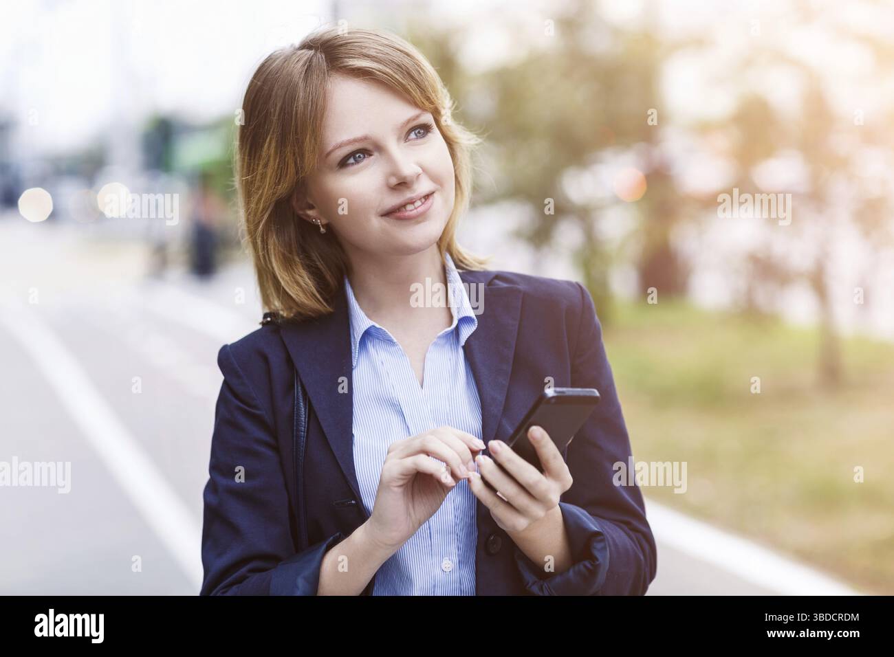 Thoughtful businesswoman sending message with smartphone outdoors Stock Photo