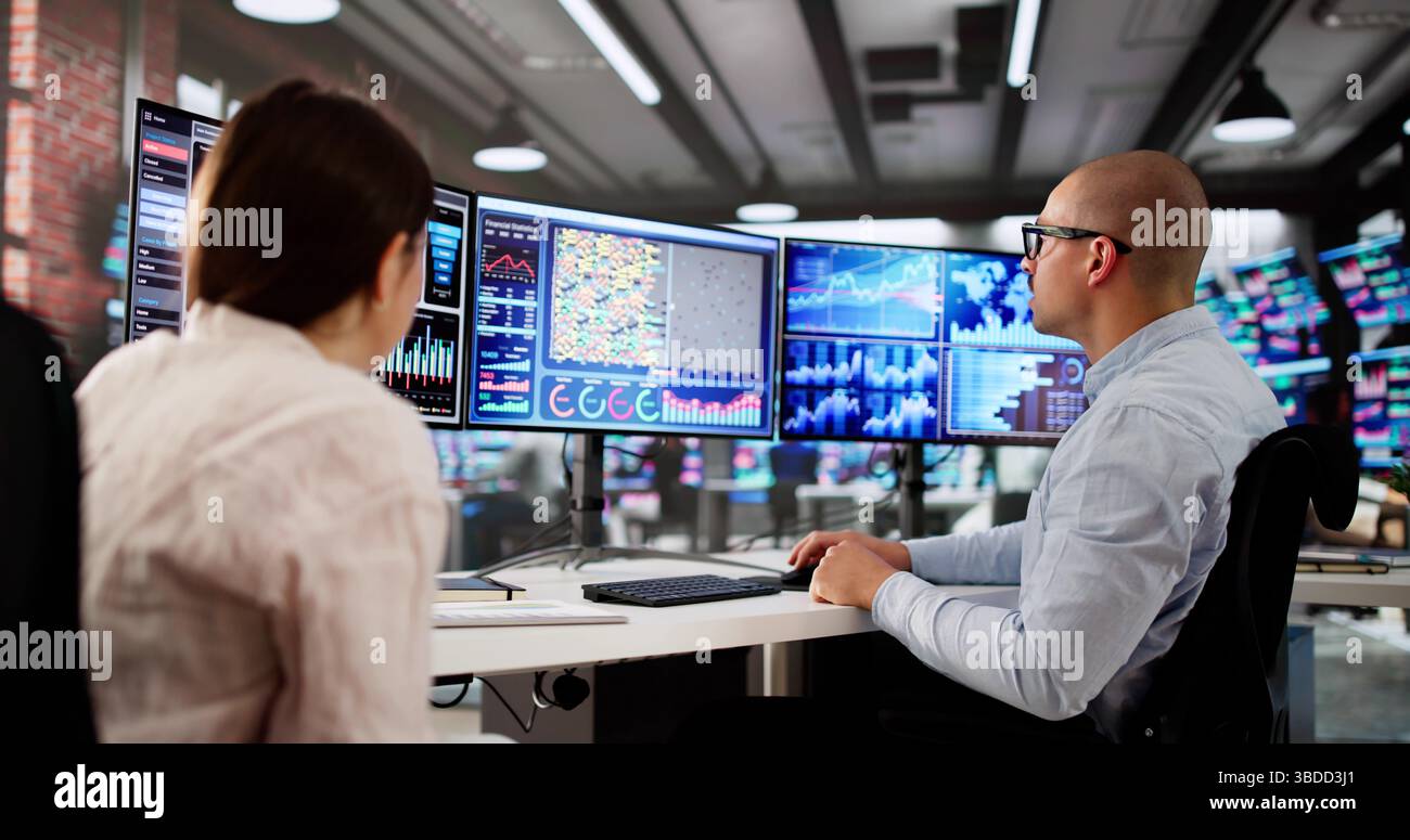 Man And Woman Analyzing Financial Data On Computer Dashboard Together. Stock Photo