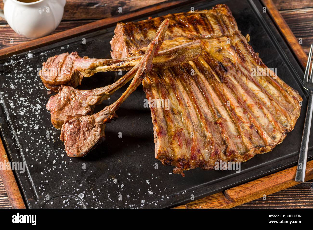 Lamb racks grilled with herbs and sauce on a stone board Stock Photo
