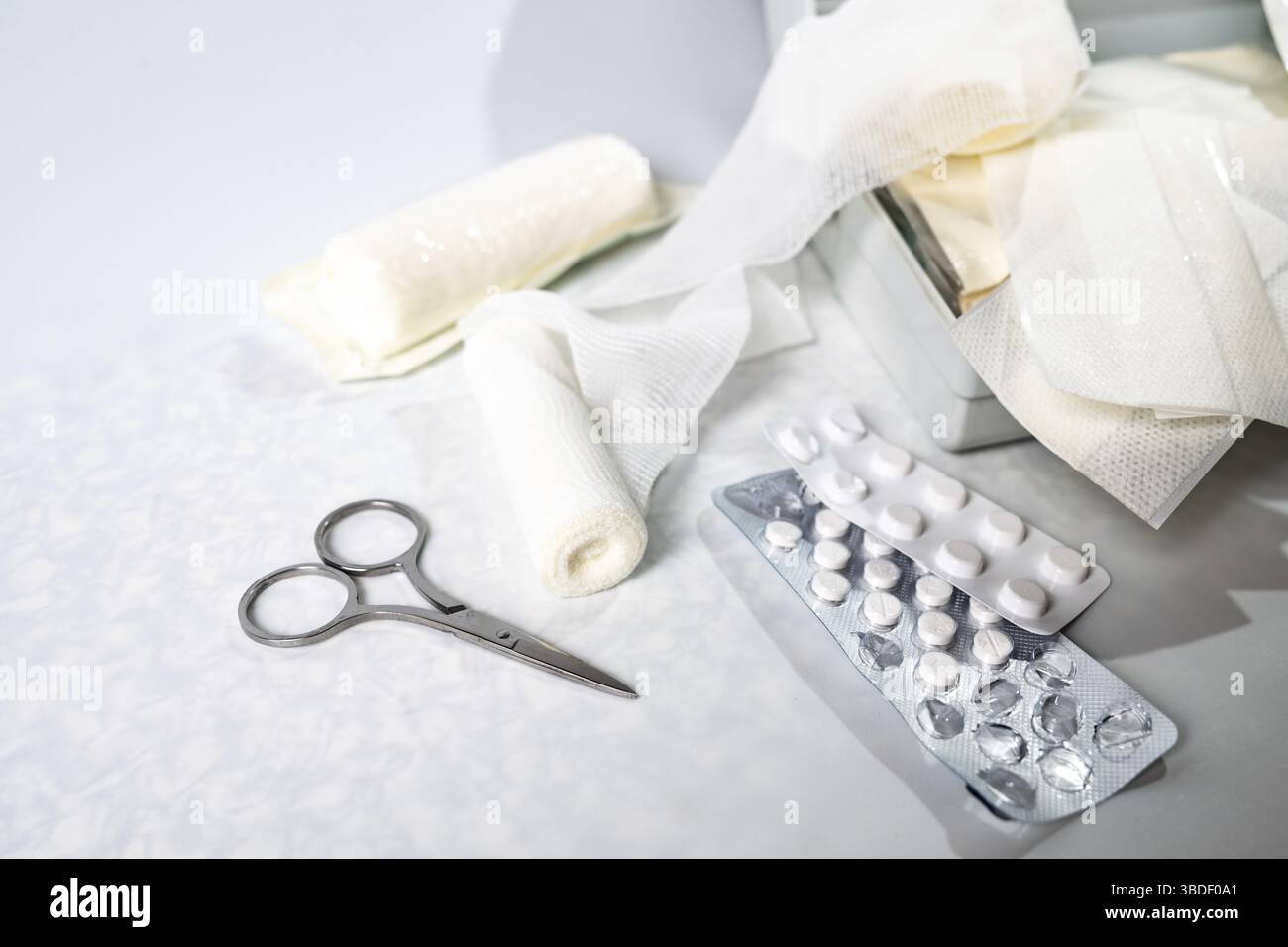 Medical supplies like bandages, plasters, pills and scissors from a first aid kit or home medicine chest on a light gray background, copy space, selec Stock Photo