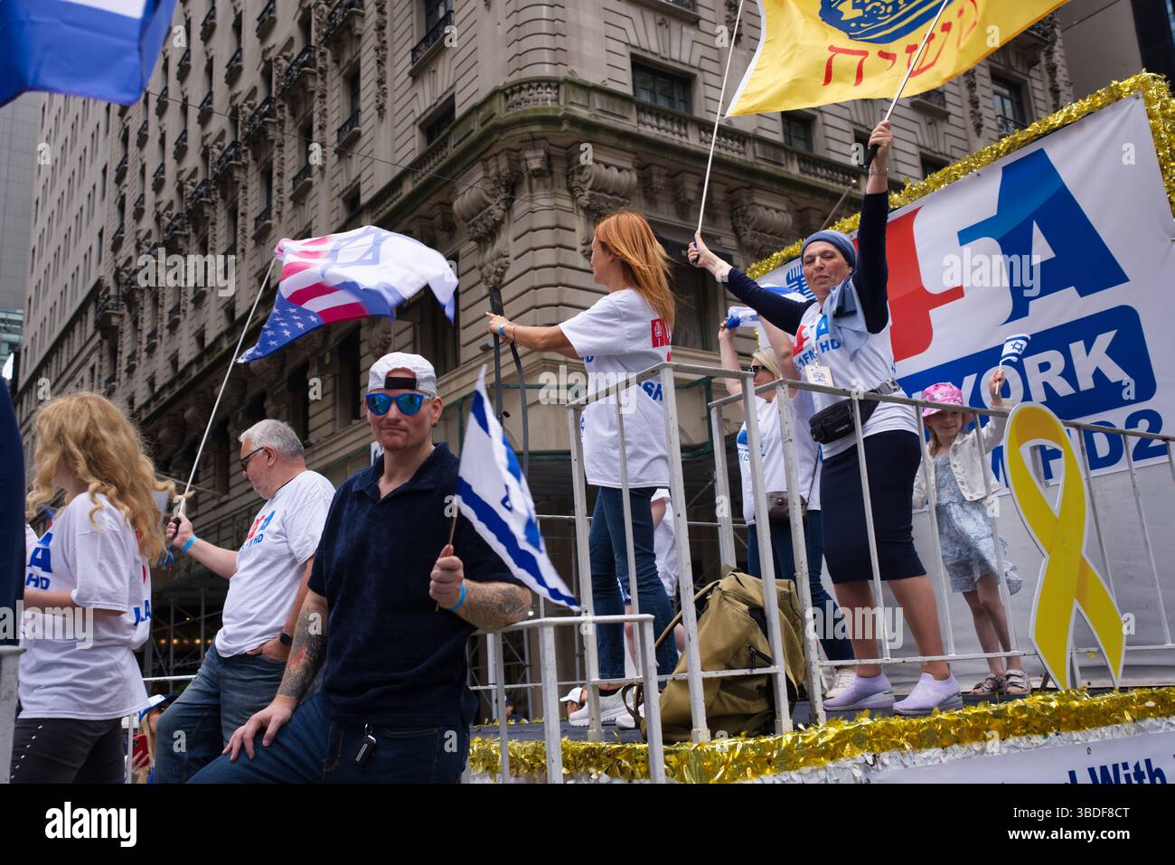 A parade float featuring people waving Israeli and American flags ...