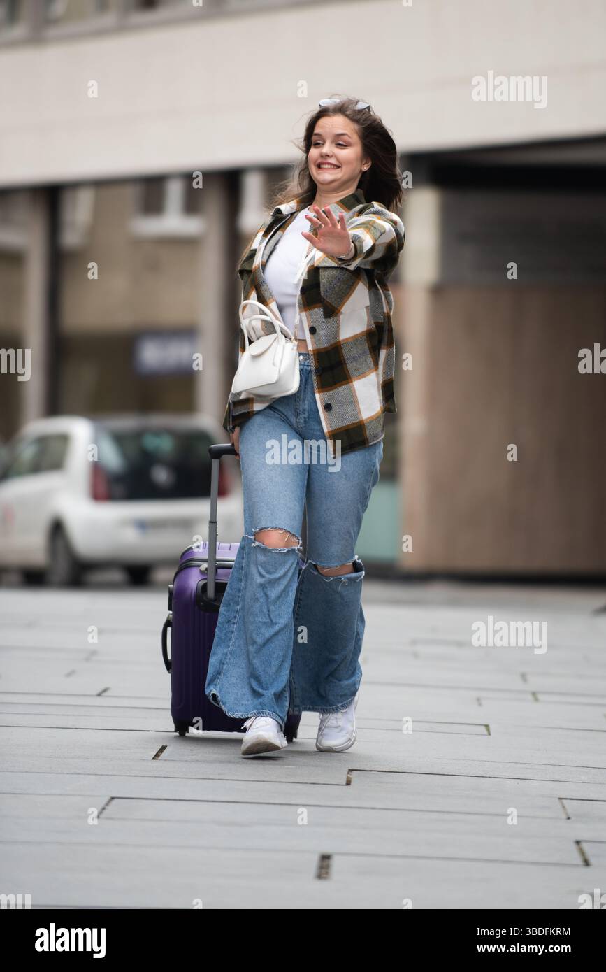 Young Woman Joyfully Walking with Luggage.  Stock Photo