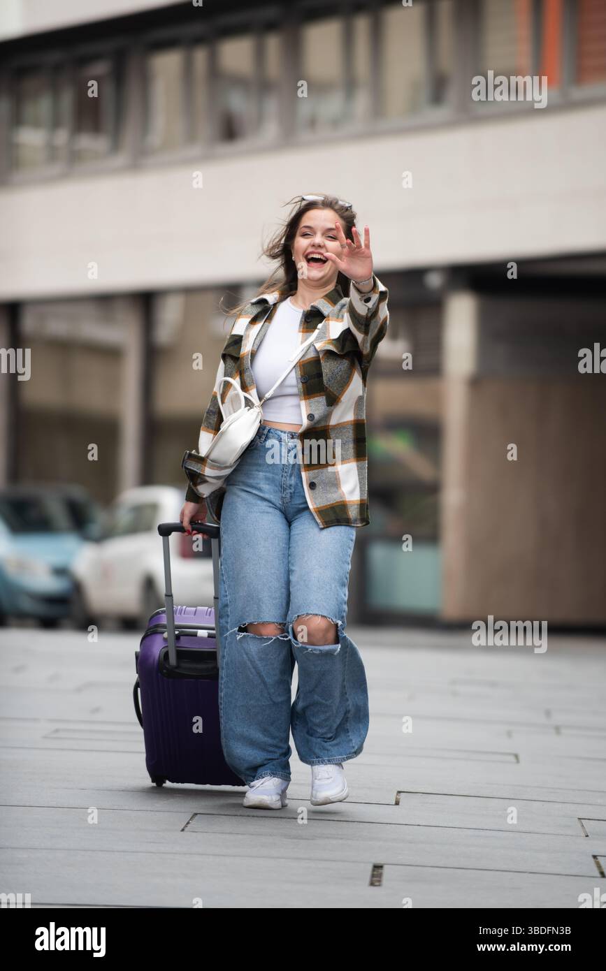 Young Woman Joyfully Walking with Luggage.  Stock Photo