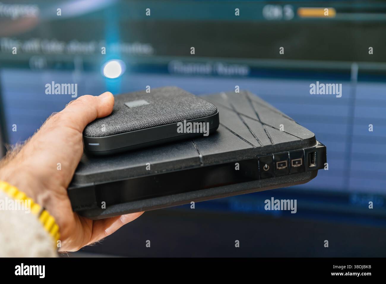 Paris, France - Feb 17, 2025: A hand holds two Orange Livebox internet TV routers, with an older generation box at the bottom featuring buttons and po Stock Photo
