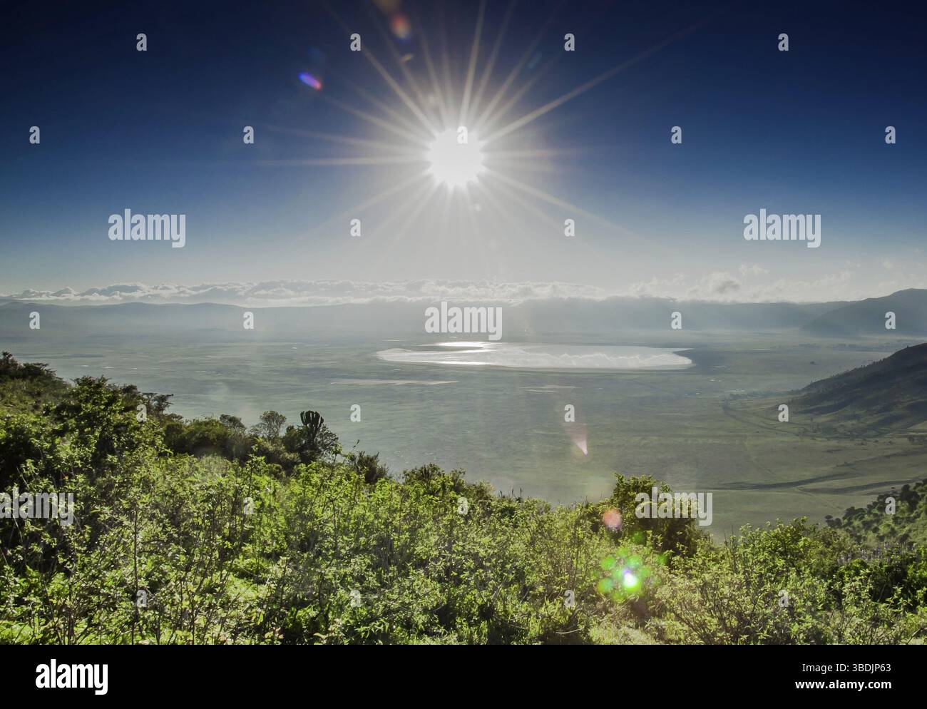 A view of the Ngorongoro Crater, with lake Magadi visbible in the distance infront of the clowds which cover the crater rim on the far side, as it is Stock Photo