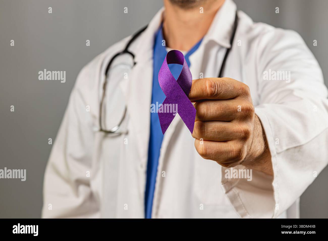 A healthcare worker displays a purple ribbon, a symbol of awareness for ...