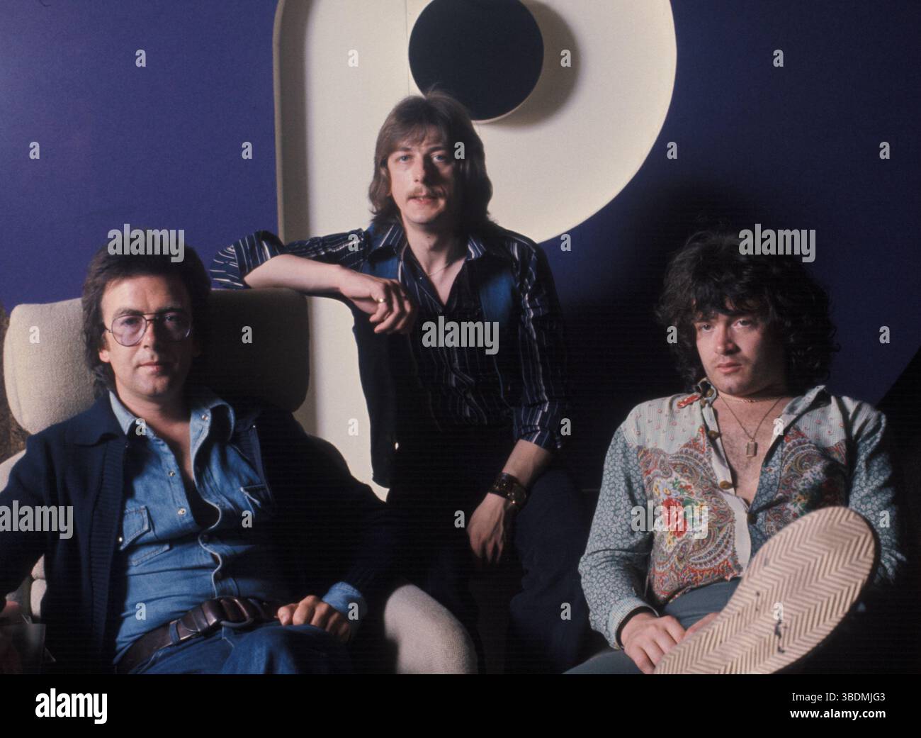 Trapeze, 1976. Trio featuring Glenn Hughes after Deep Purple had split. Left to right, Mel Galley on guitar, Dave Holland on drums, Glenn Hughes vocals and bass.  They did some US concert dates but Glenn was unable to finish the tour.  This photograph was taken at the Newman Street offices of Purple Records. Stock Photo