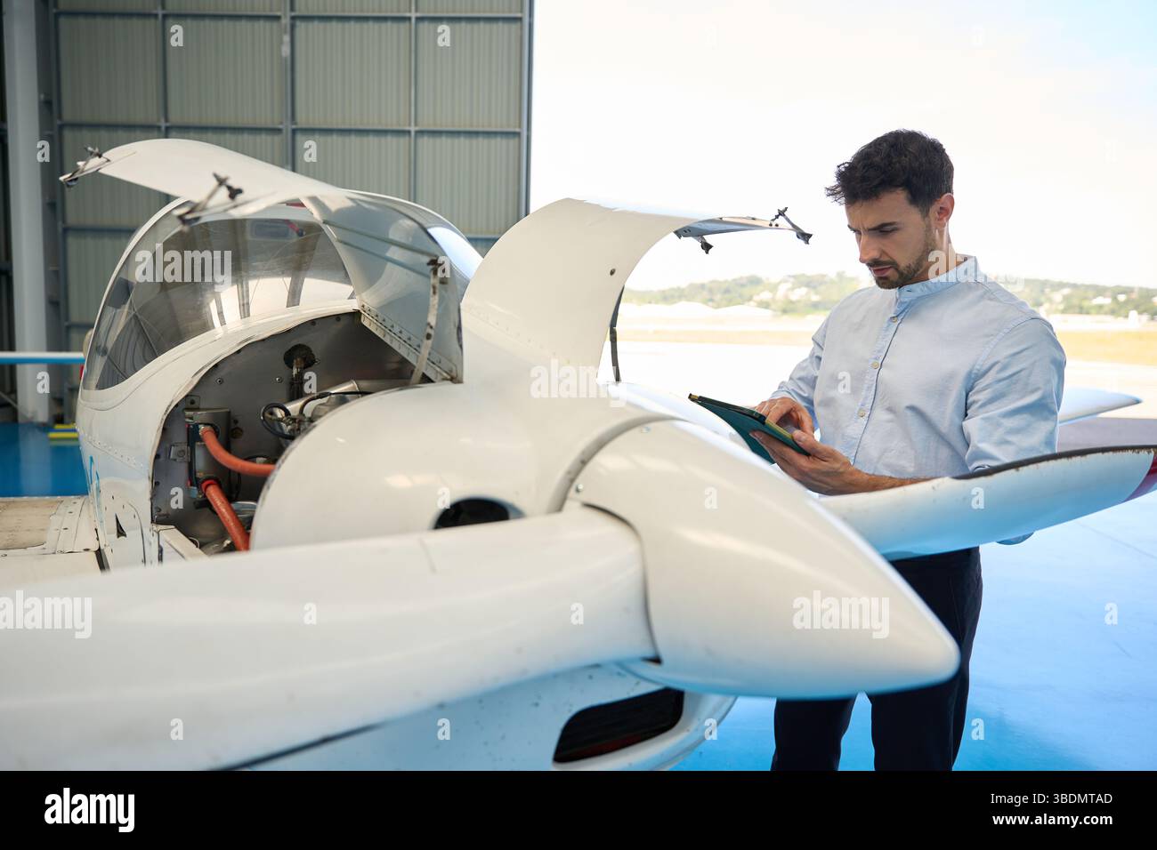 Pilot Inspecting Engine Aircraft mechanic inspecting engine with digital tablet in hangar Stock ...