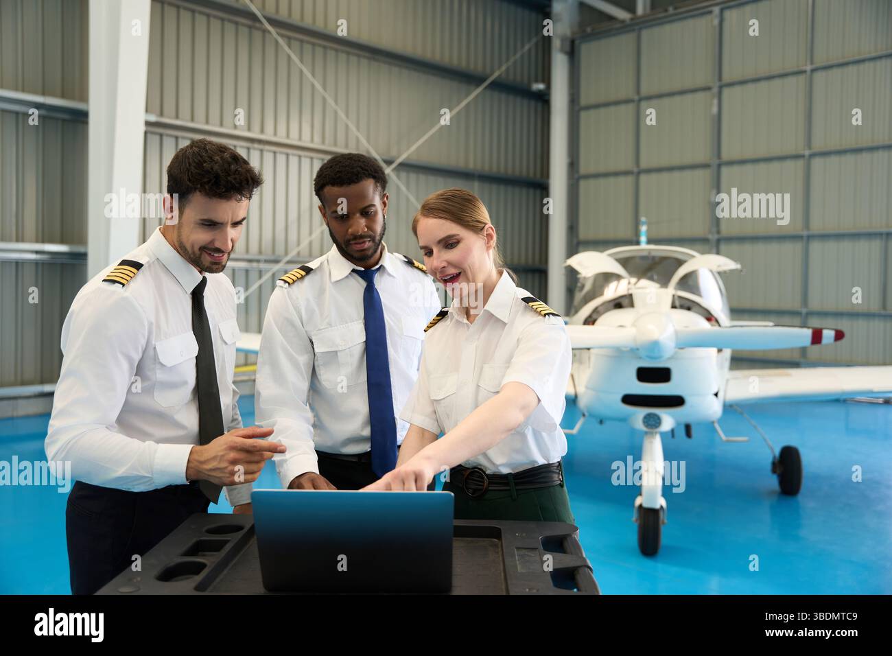 Aircraft maintenance crew using laptop in hangar with small airplane Stock Photo