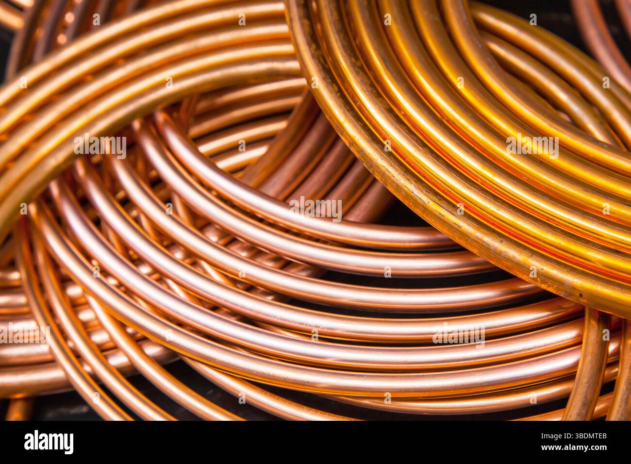 Twisted new copper tubes on a black background Stock Photo - Alamy