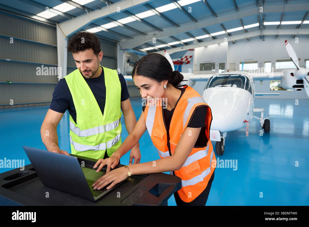 Aircraft mechanics using laptop in hangar with small airplane Stock Photo