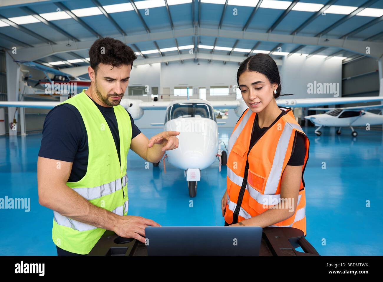 Aircraft mechanics using laptop, discussing maintenance in hangar Stock Photo