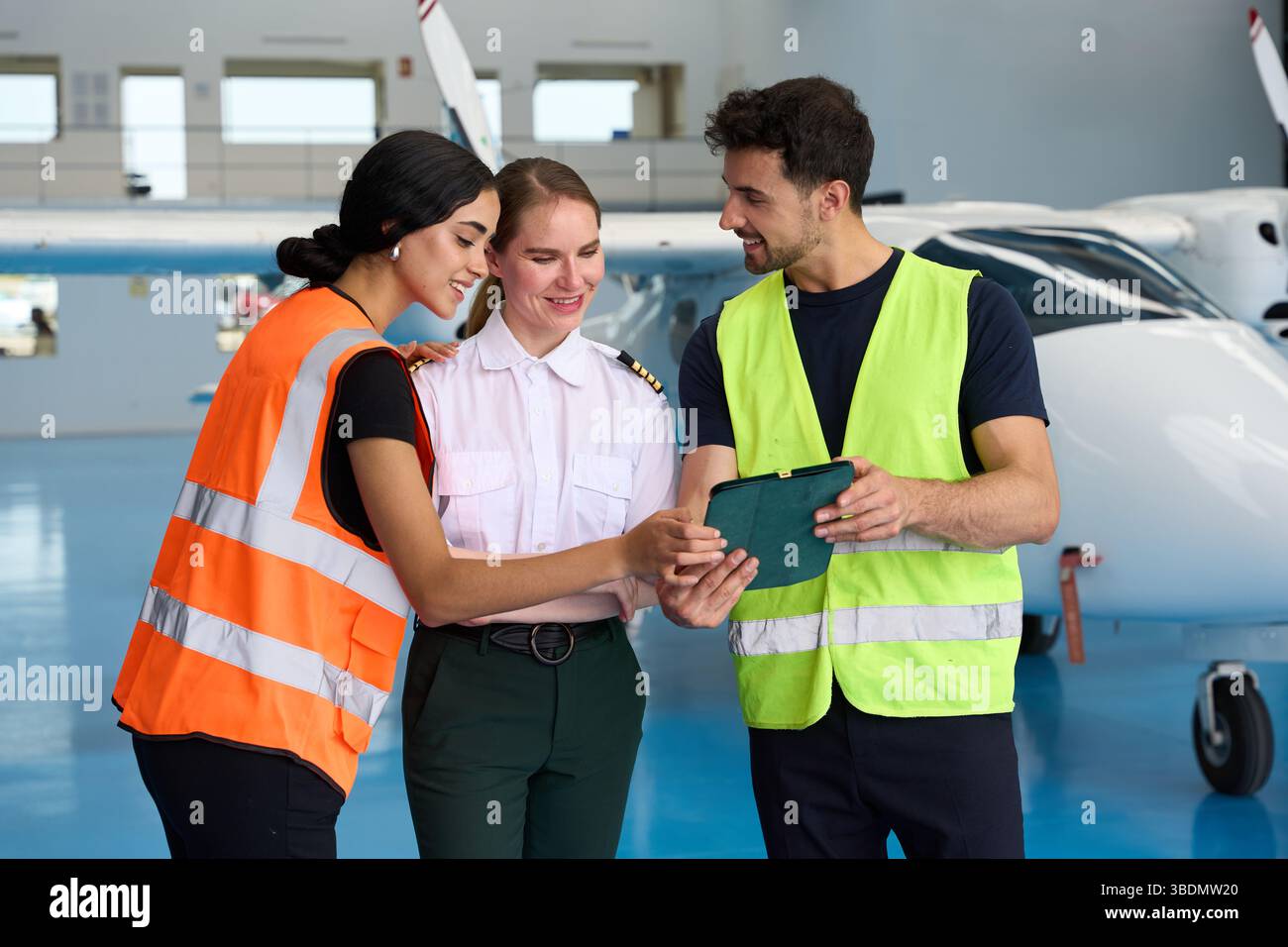 Aviation students and pilot using tablet in hangar Stock Photo