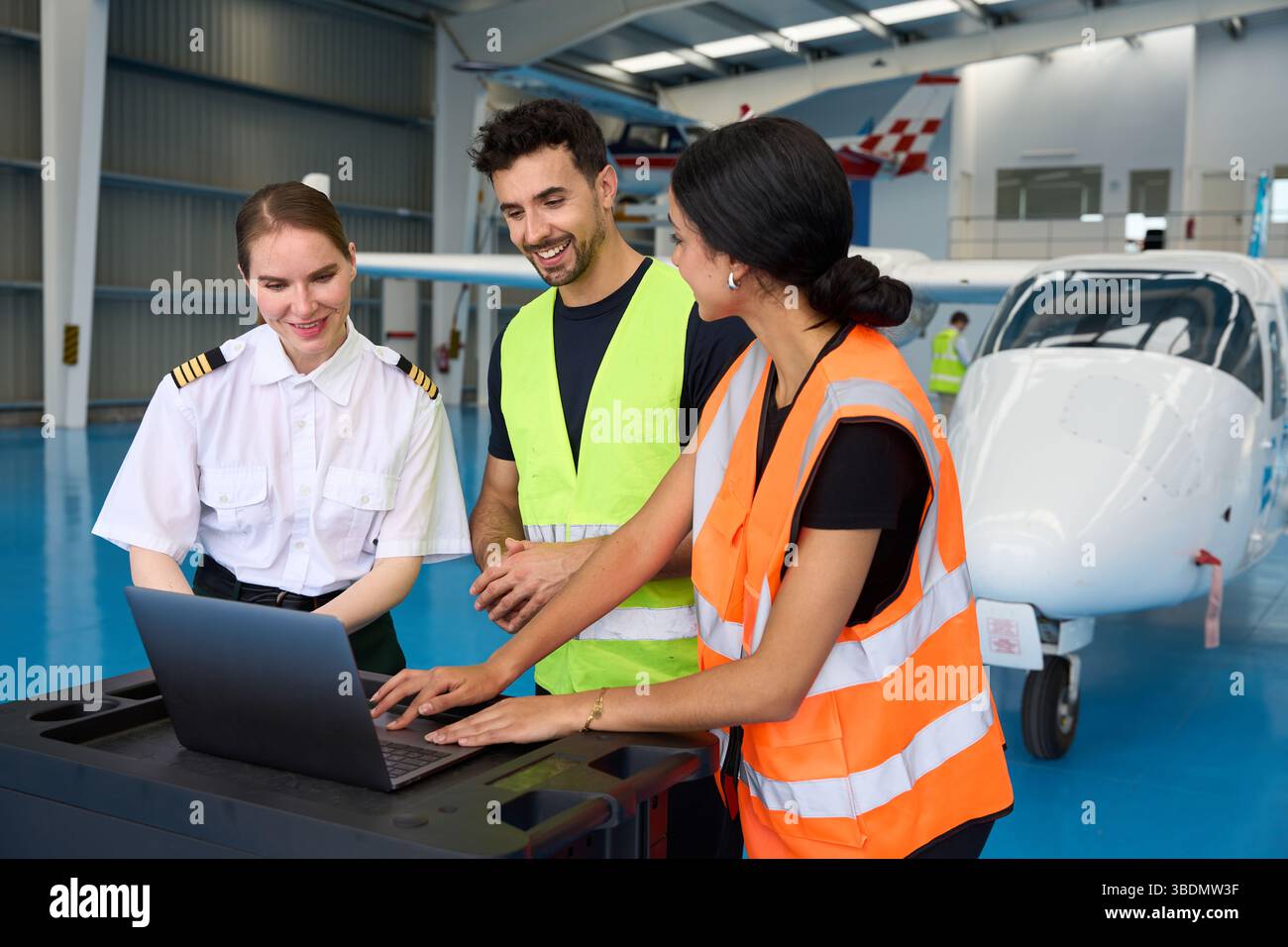 Aviation students and pilot using laptop in aircraft hangar Stock Photo