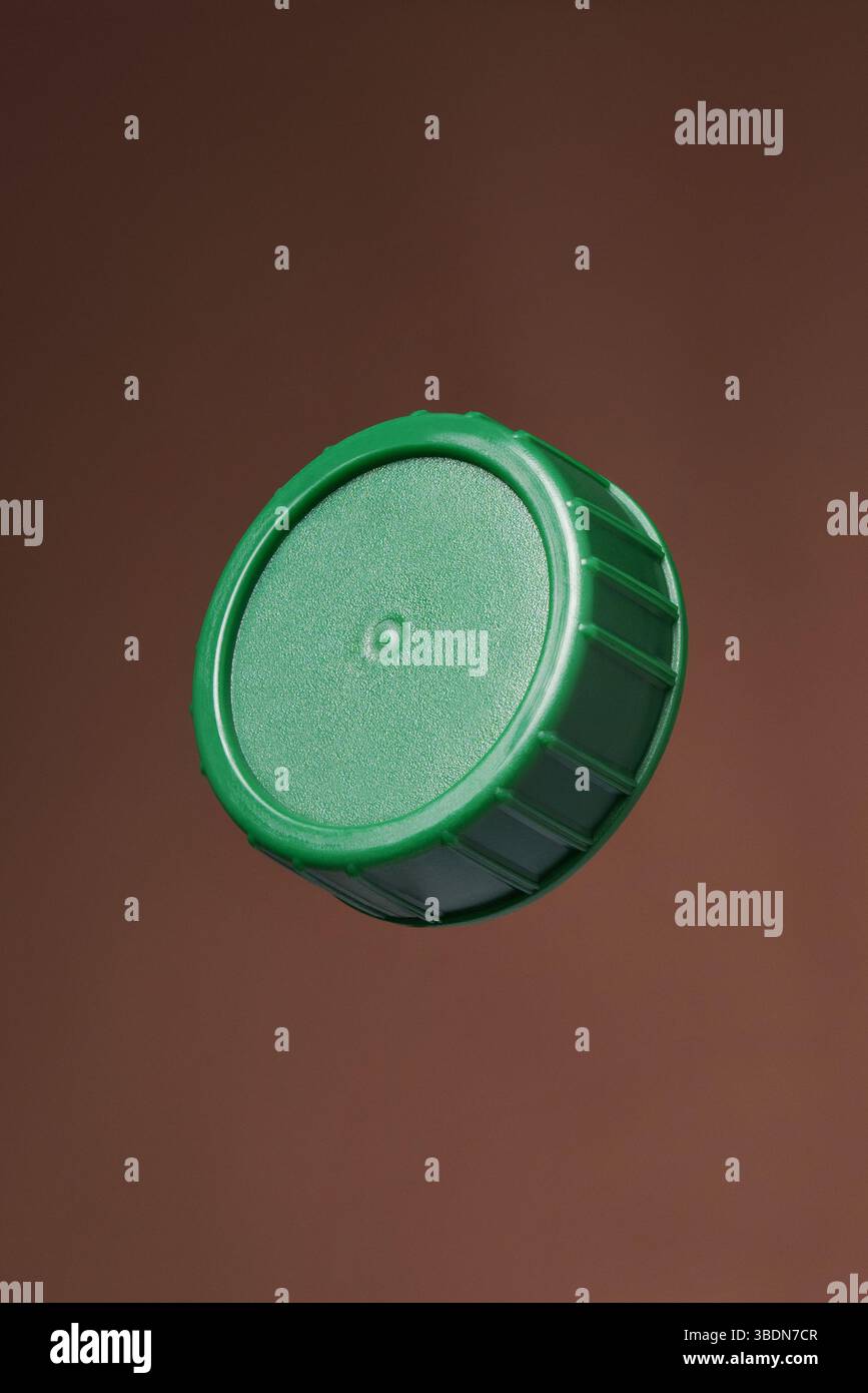 Green plastic bottle cap on a brown background. Close up. Stock Photo