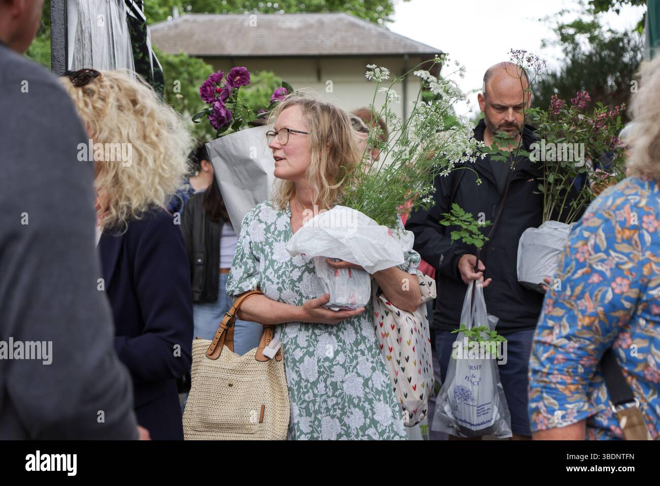Stephen Colfer Rhs London, UK. 24th May, 2025. A woman carrying pots of flowers departs ...