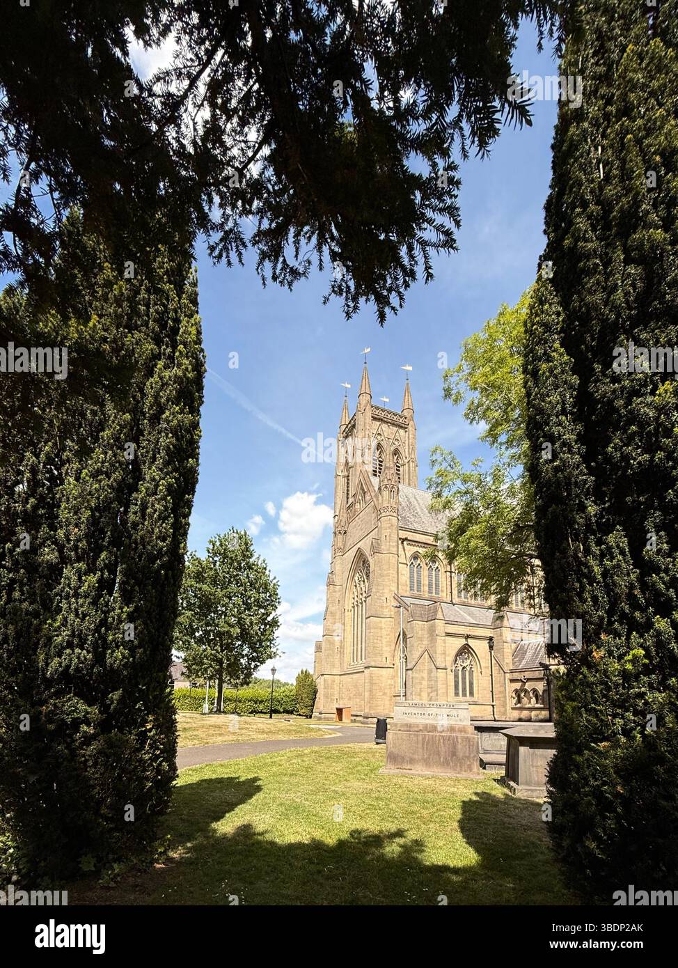 Tomb of Samuel Crompton (inventor of the Mule) in graveyard of Bolton parish church. St Peter’s church in background framed by trees in church yard - Smartphone Captured Stock Image