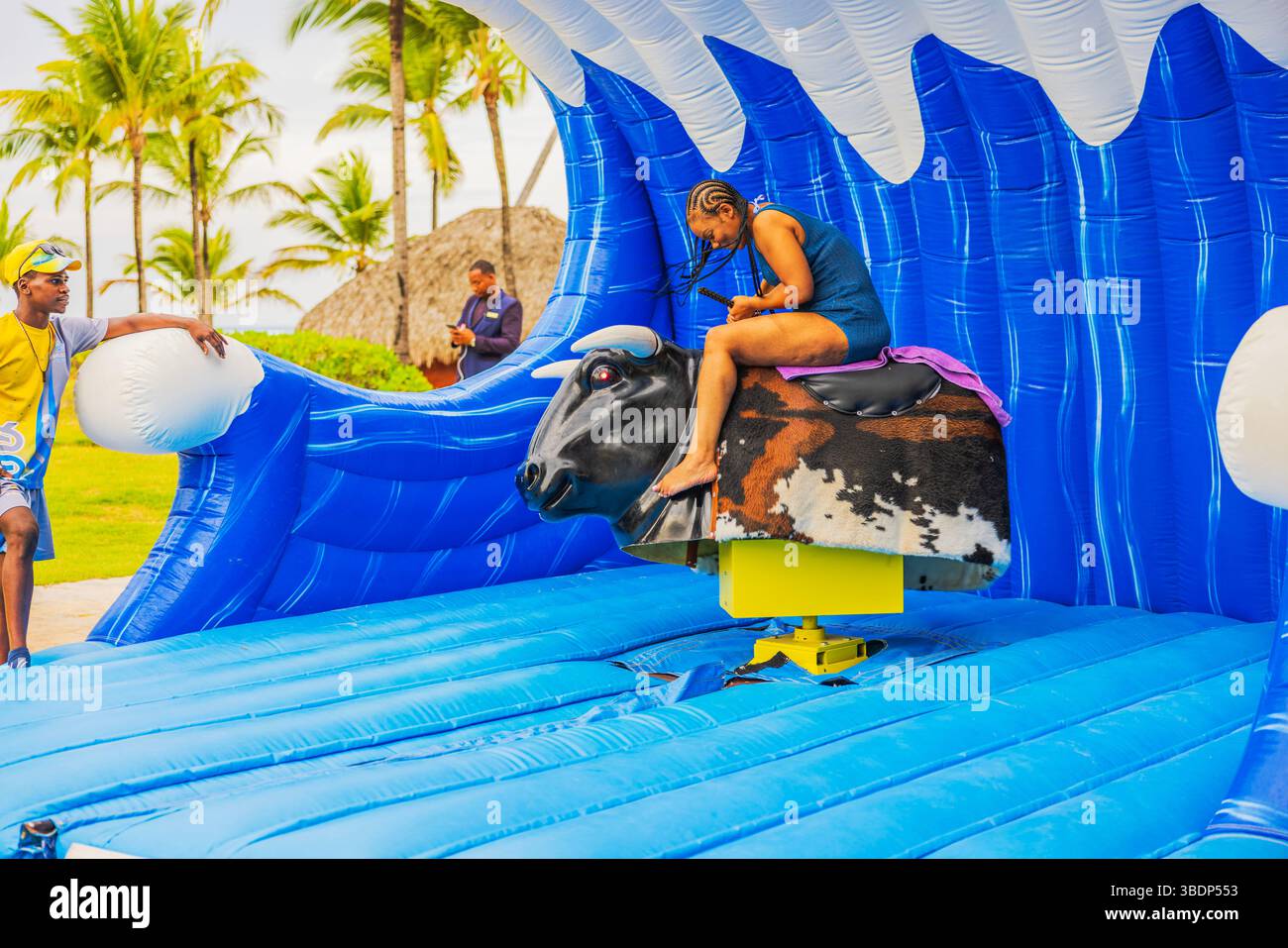 Woman in beach coverup concentrates while riding inflatable mechanical ...
