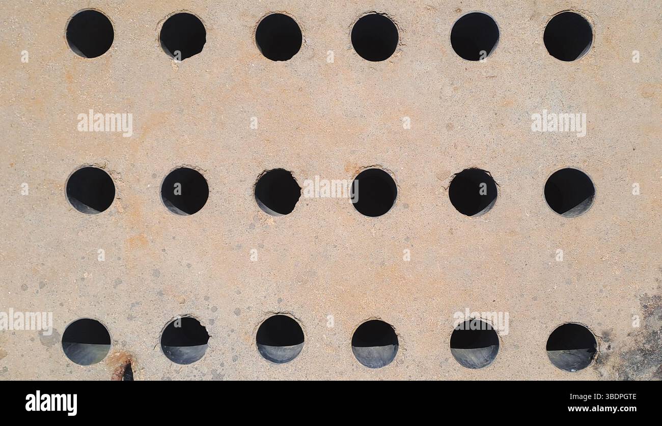 Rusty metal plate featuring evenly spaced circular cutouts Stock Photo