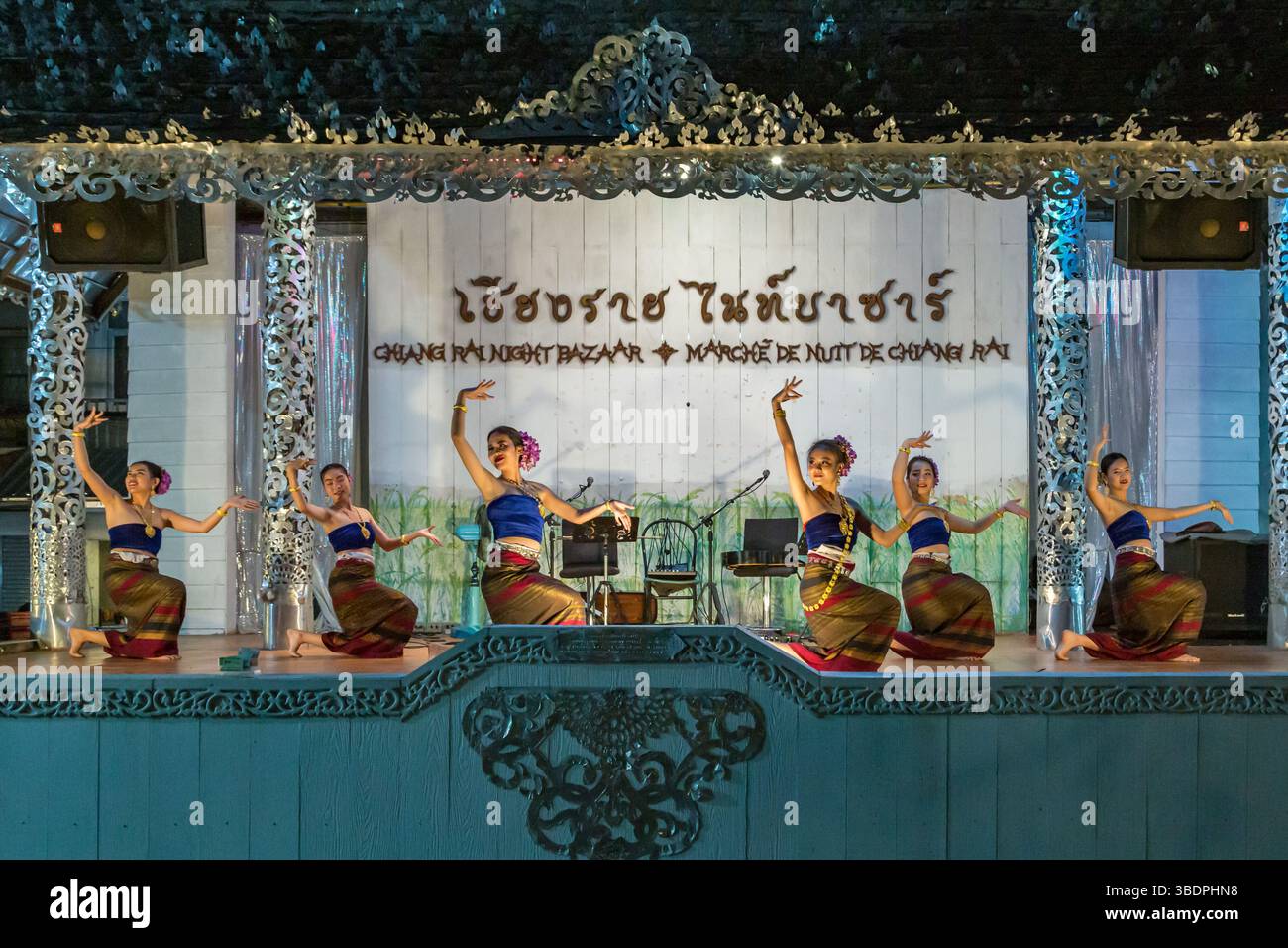 Traditional Thai dancers perform on a lighted stage at the night market ...