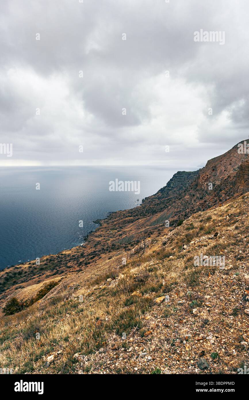 Coastal landscape with rugged cliffs and deep blue ocean under cloudy ...
