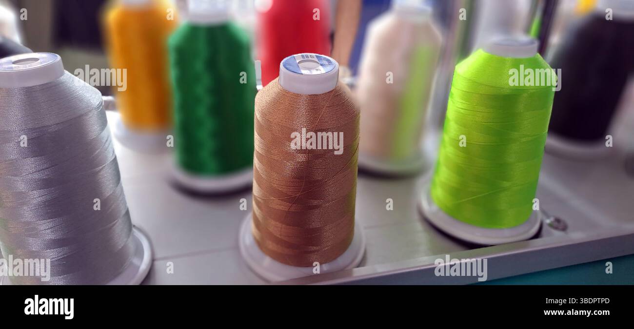 Spools of brightly colored thread are arranged on an embroidery machine, ready for use Stock Photo