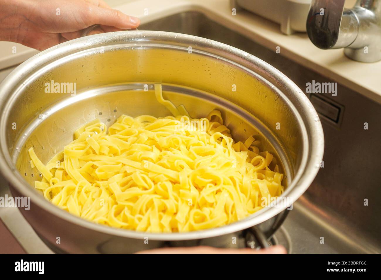 Cook tagliatelle pasta, drained in a colander Stock Photo