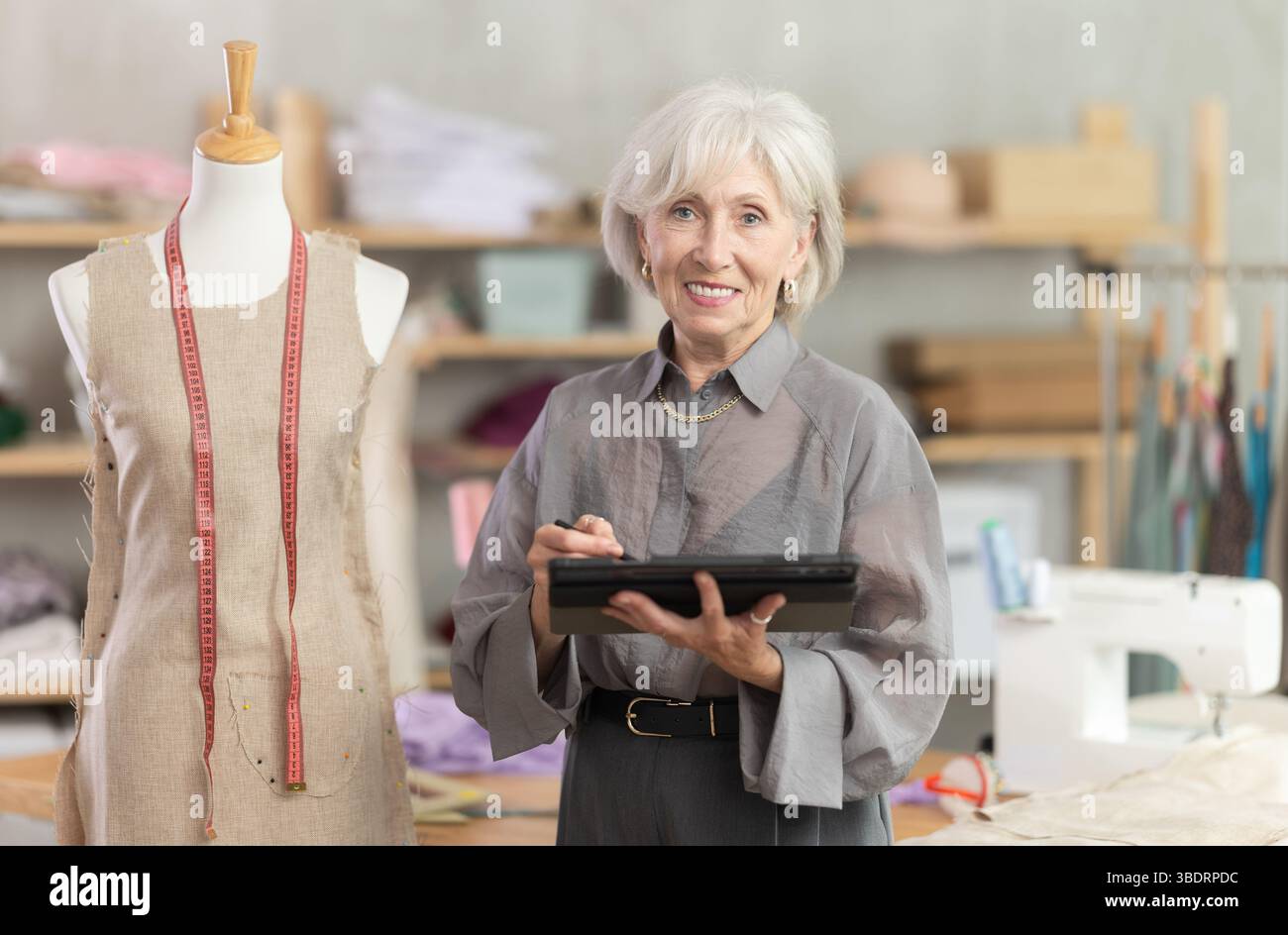 Woman dressmaker makes pattern using tablet Stock Photo