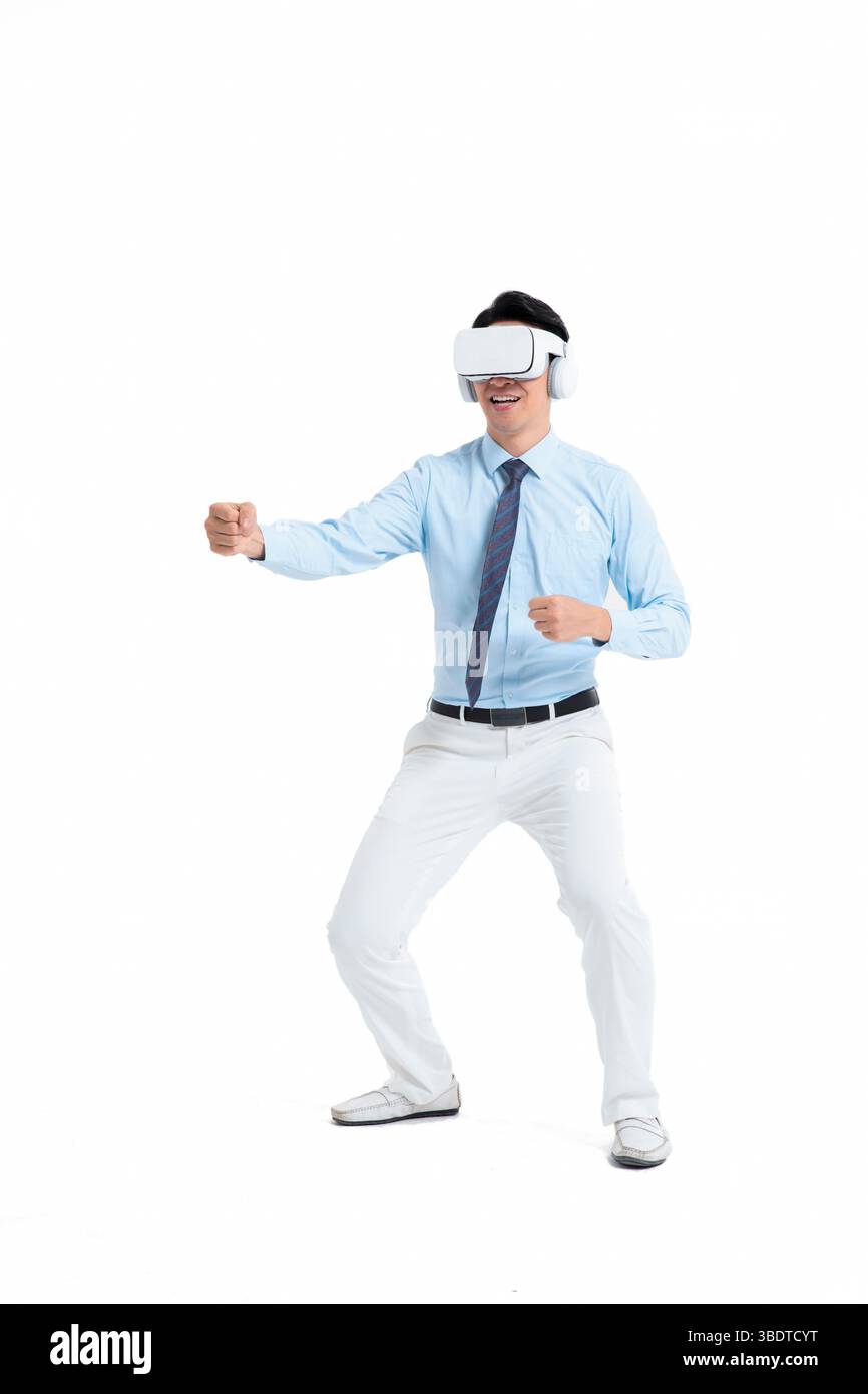 A suited man wearing a VR headset waves both hands vigorously Stock Photo