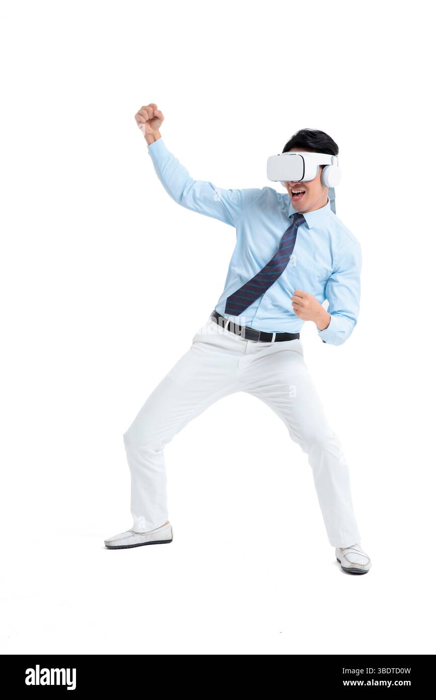 A suited man wearing a VR headset waves both hands vigorously Stock Photo
