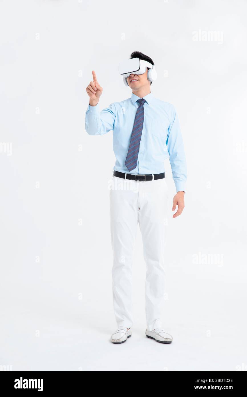 A suited man wearing a VR headset waves both hands vigorously Stock Photo