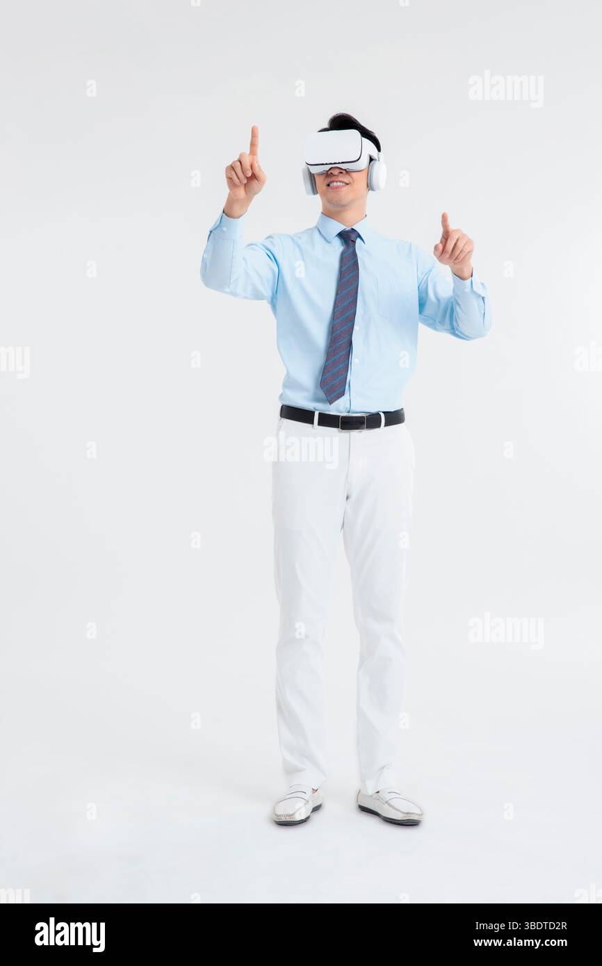 A suited man wearing a VR headset waves both hands vigorously Stock Photo