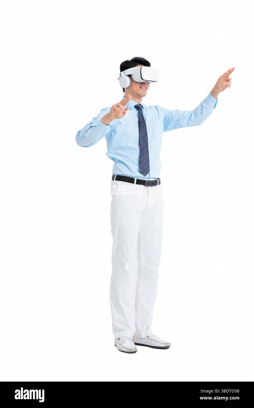 A suited man wearing a VR headset waves both hands vigorously Stock Photo