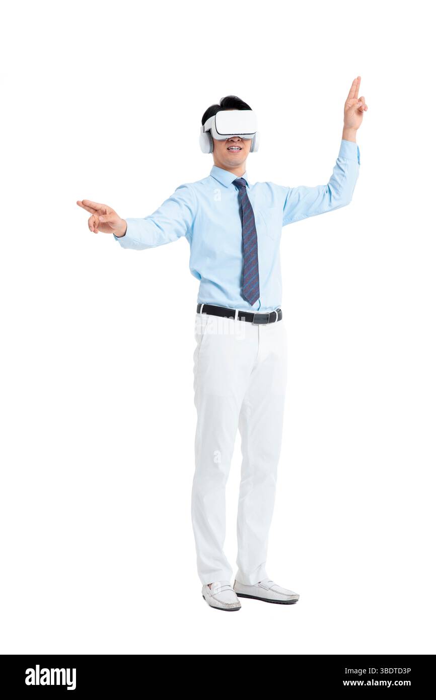 A suited man wearing a VR headset waves both hands vigorously Stock Photo