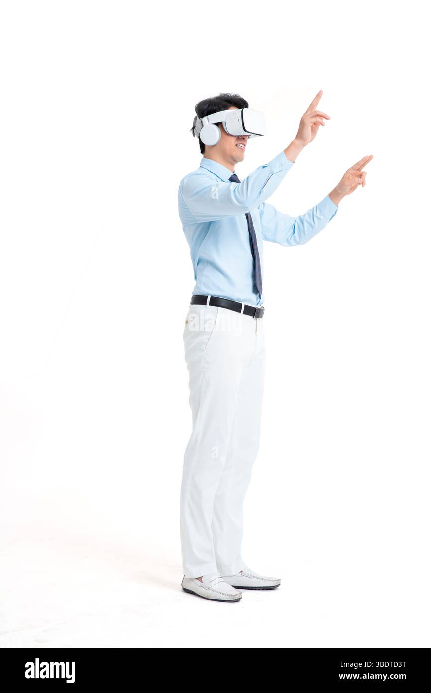 A suited man wearing a VR headset waves both hands vigorously Stock Photo