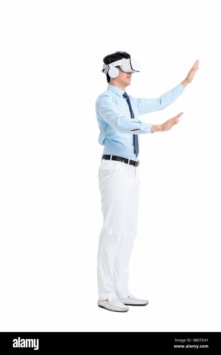 A suited man wearing a VR headset waves both hands vigorously Stock Photo