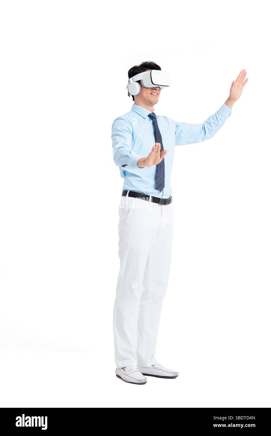 A suited man wearing a VR headset waves both hands vigorously Stock Photo