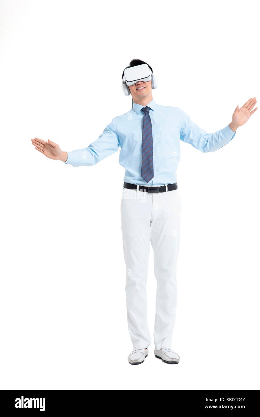 A suited man wearing a VR headset waves both hands vigorously Stock Photo