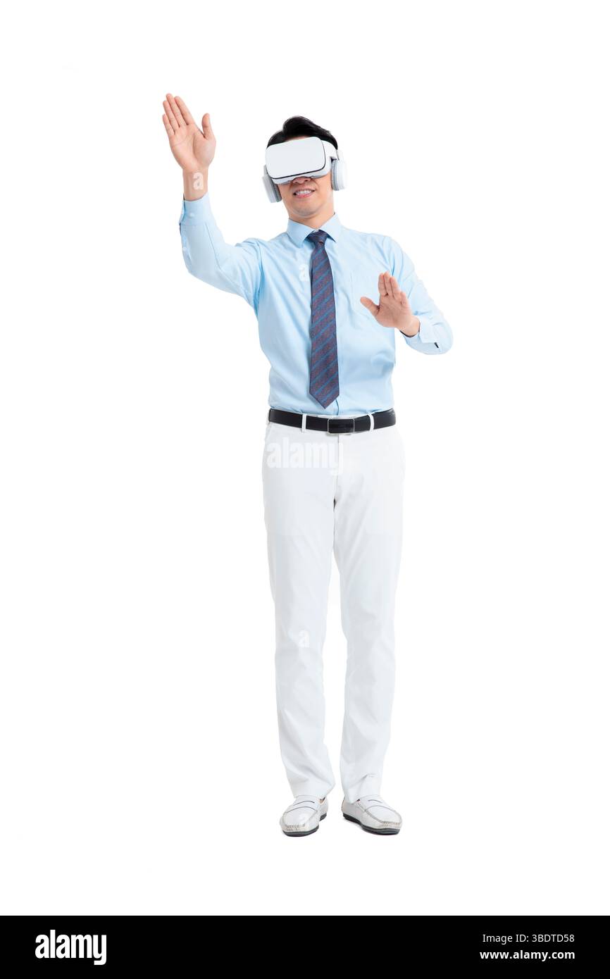 A suited man wearing a VR headset waves both hands vigorously Stock Photo