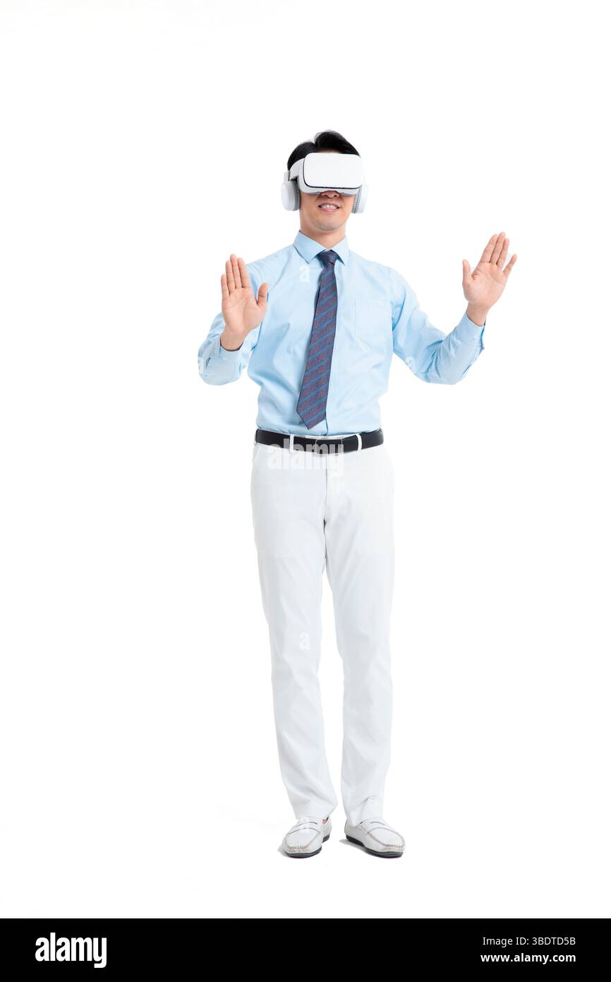 A suited man wearing a VR headset waves both hands vigorously Stock Photo