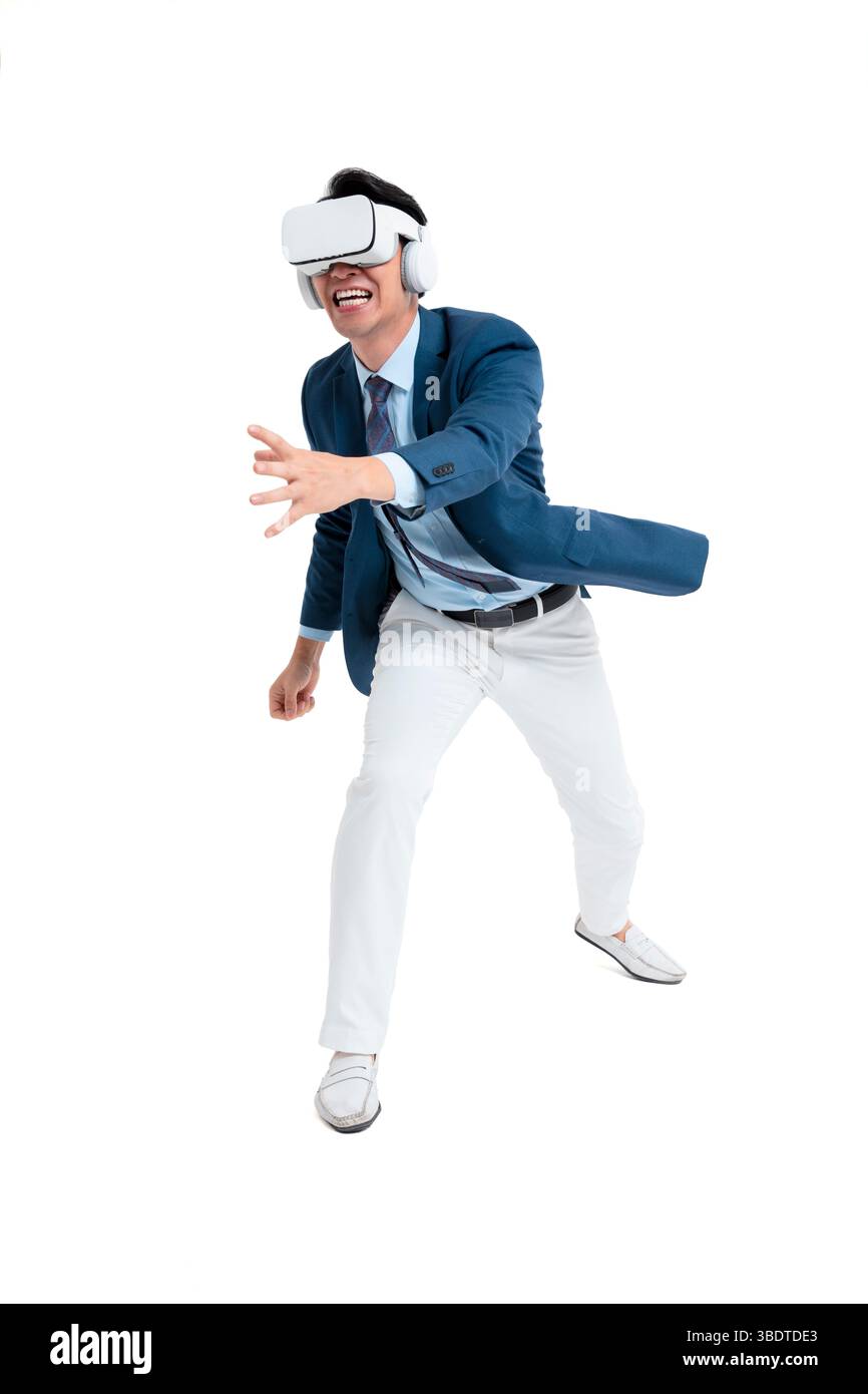 A suited businessman interacts with virtual objects through frenzied gestures, wearing VR/AR headset Stock Photo