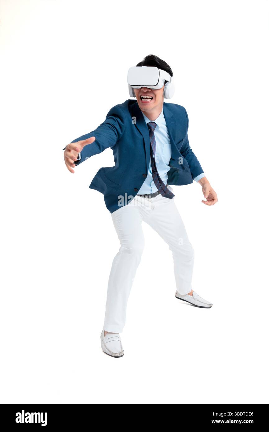 A suited businessman interacts with virtual objects through frenzied gestures, wearing VR/AR headset Stock Photo