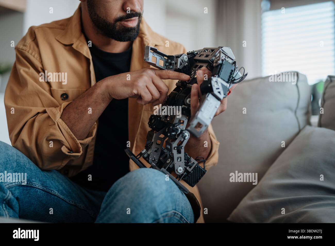 Handsome engineer student working on robot project at home. Stock Photo