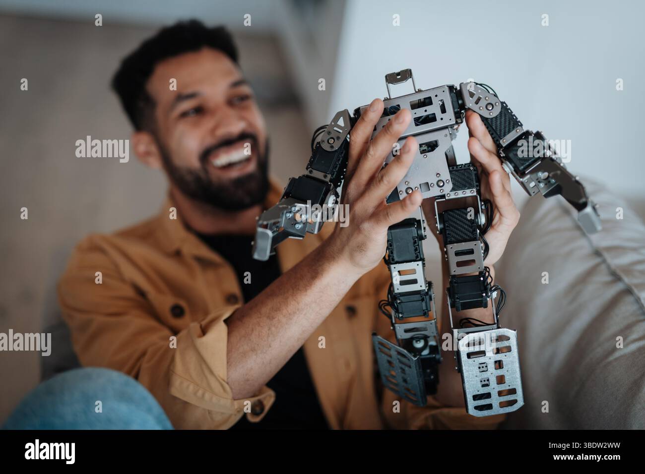 Handsome engineer student working on robot project at home. Stock Photo