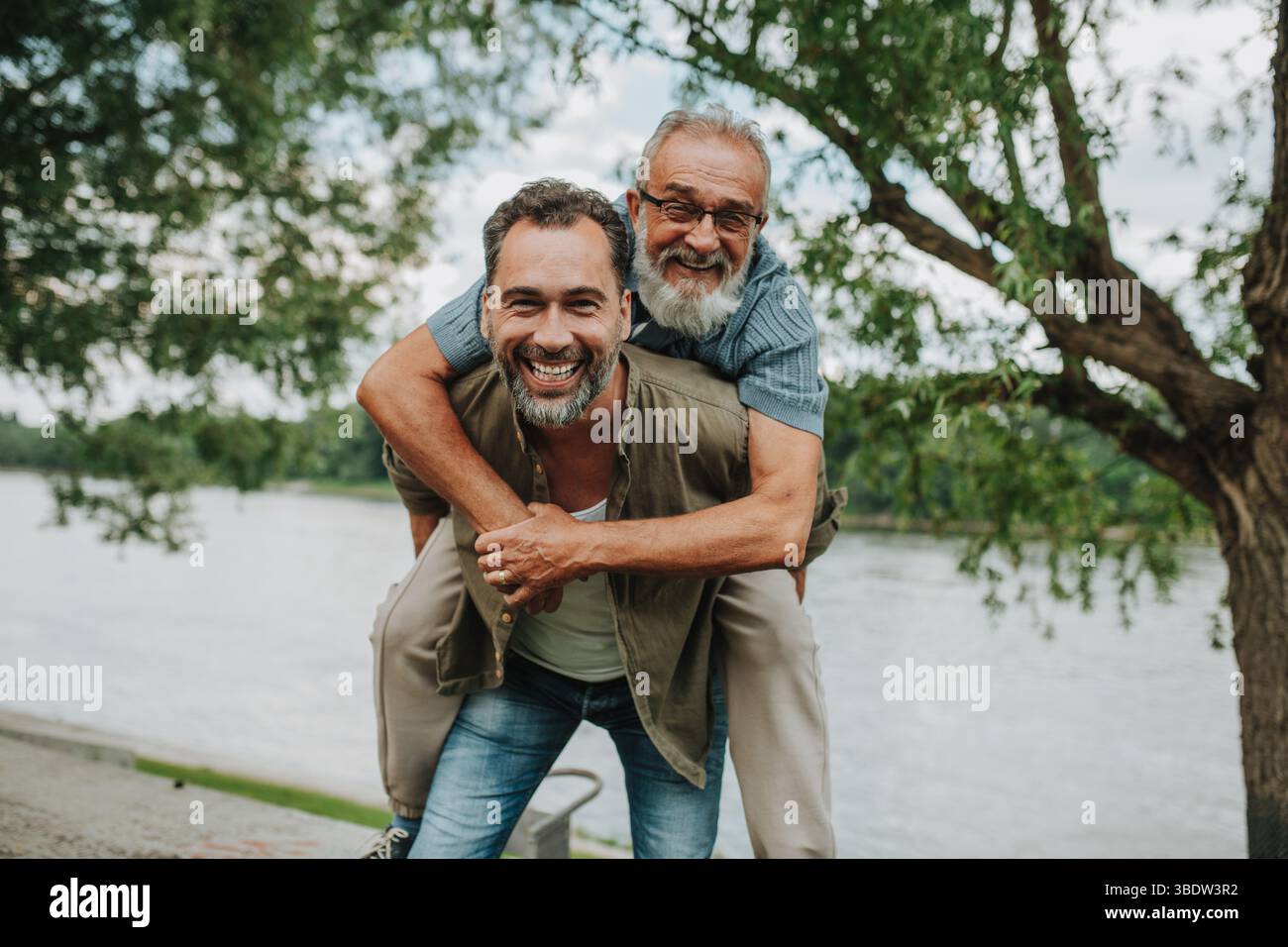 Adult son carrying older father on his back Stock Photo - Alamy