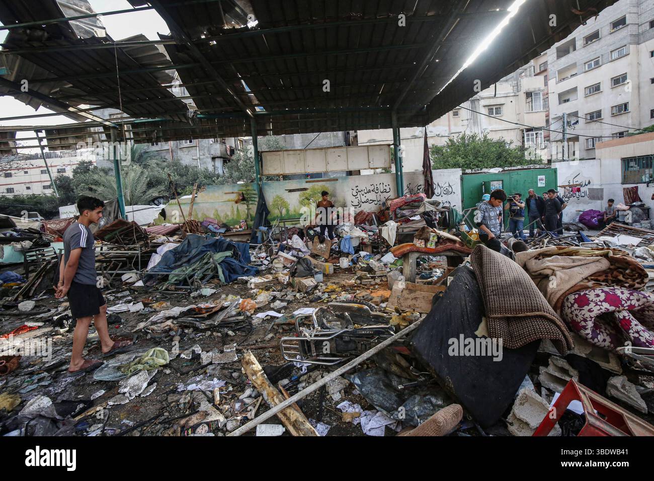Palestinians inspect the area among the rubbles of destroyed building